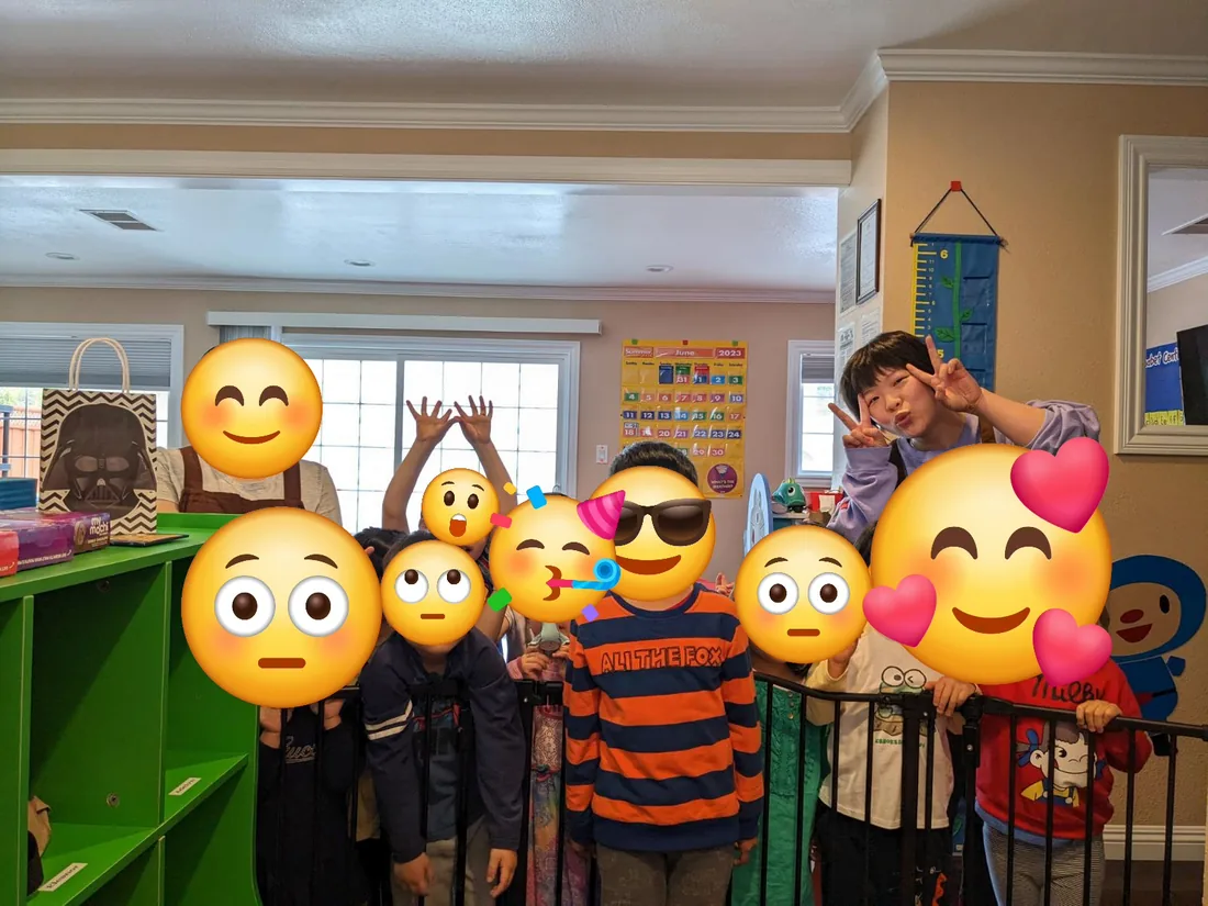A classroom group of toddlers and preschoolers waving and posing together at the end of the day