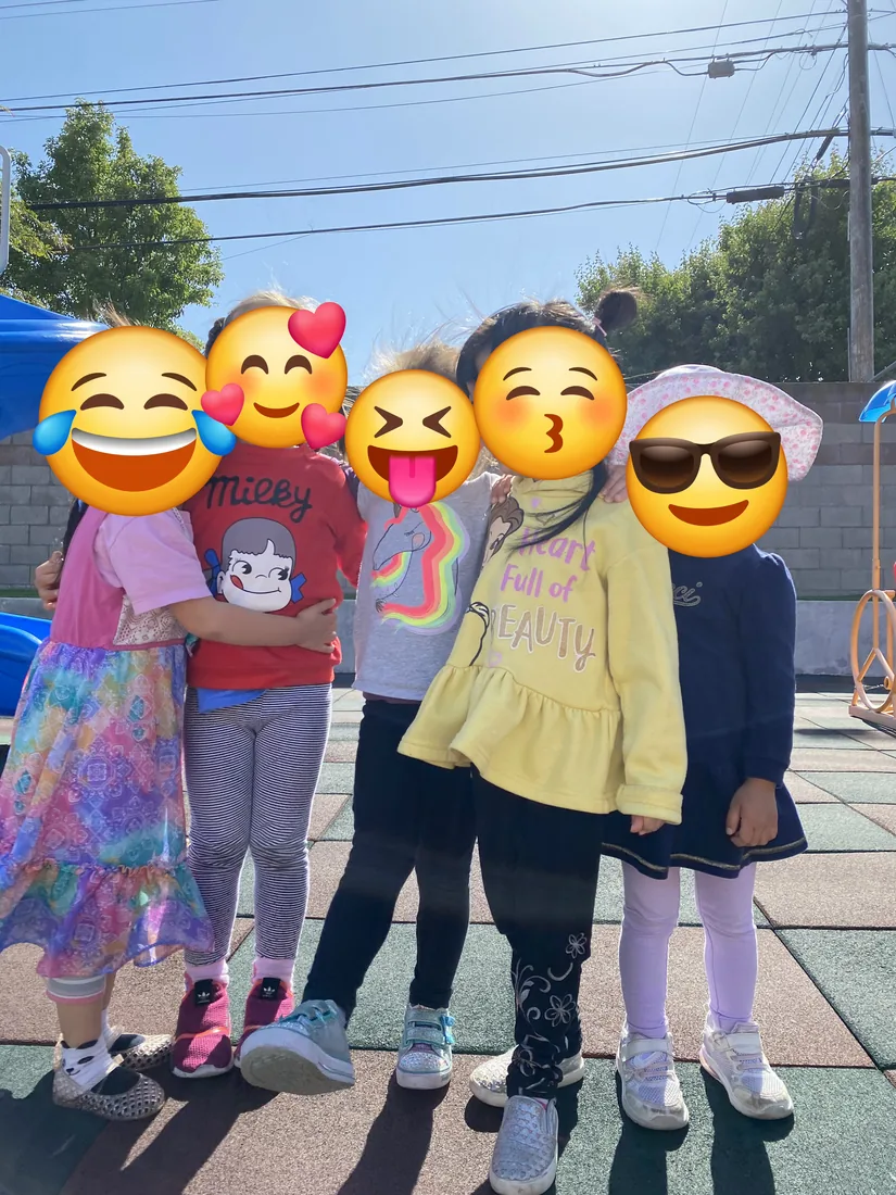 A group of preschoolers with their arms around each other on the playground